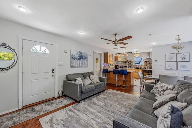 living room with dark wood-type flooring and ceiling fan with notable chandelier