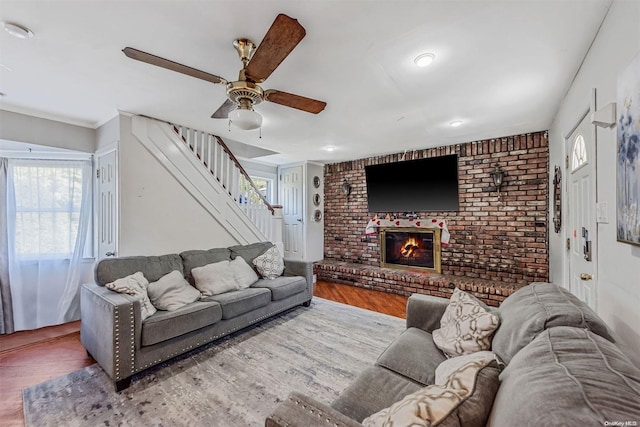 living room featuring a fireplace, light hardwood / wood-style flooring, and ceiling fan