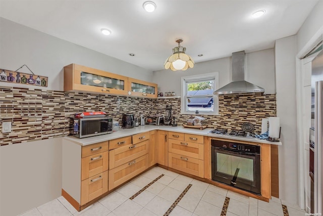 kitchen featuring appliances with stainless steel finishes, backsplash, wall chimney range hood, light brown cabinets, and light tile patterned floors