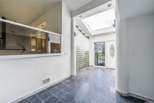 foyer entrance featuring vaulted ceiling with skylight