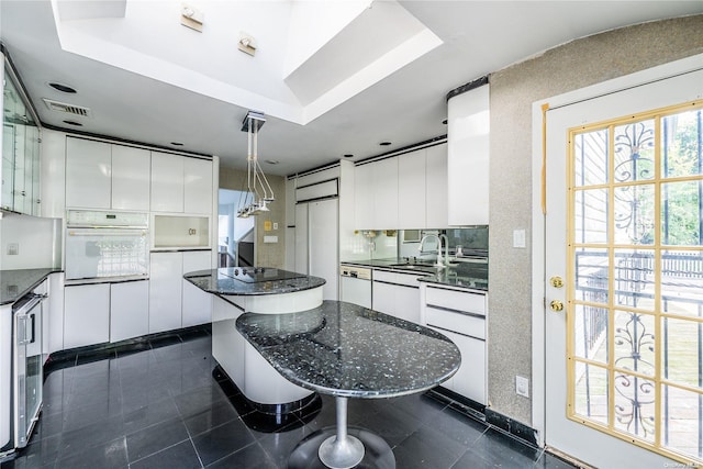 kitchen with white cabinets, a center island, white appliances, and sink