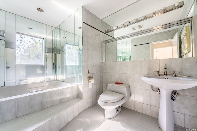 bathroom with tile patterned floors, tiled shower / bath combo, toilet, and tile walls