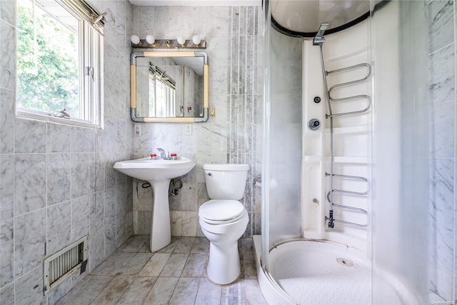 bathroom featuring sink, toilet, walk in shower, and tile walls