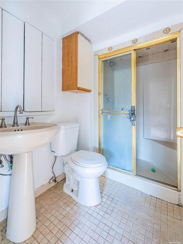 bathroom featuring tile patterned flooring, a shower with shower door, and toilet