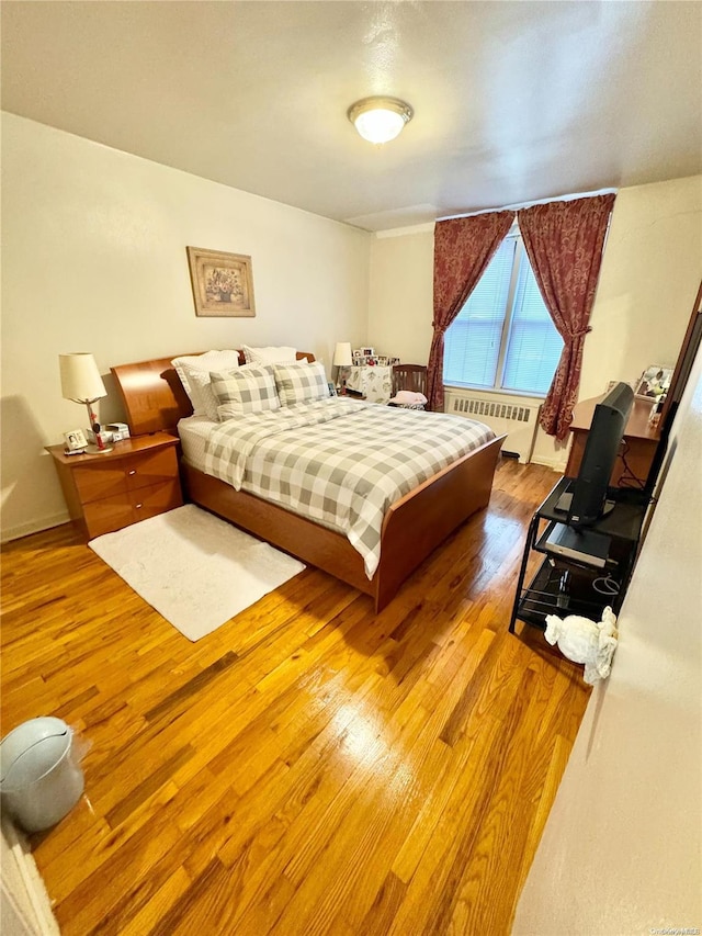 bedroom with radiator and hardwood / wood-style flooring