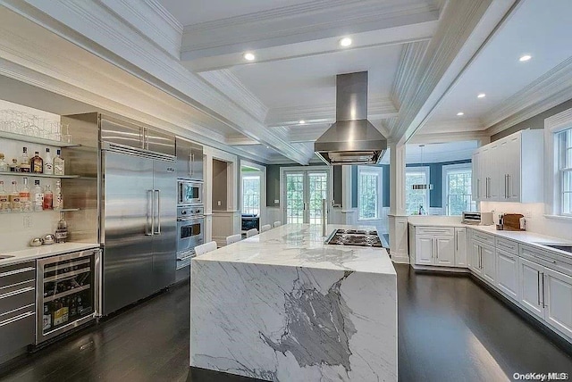 kitchen with a center island, wine cooler, built in appliances, island range hood, and white cabinets