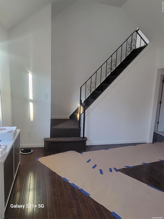 staircase featuring hardwood / wood-style floors and high vaulted ceiling