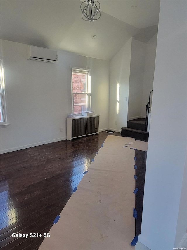 unfurnished living room with a wall mounted air conditioner, dark hardwood / wood-style flooring, radiator heating unit, and vaulted ceiling