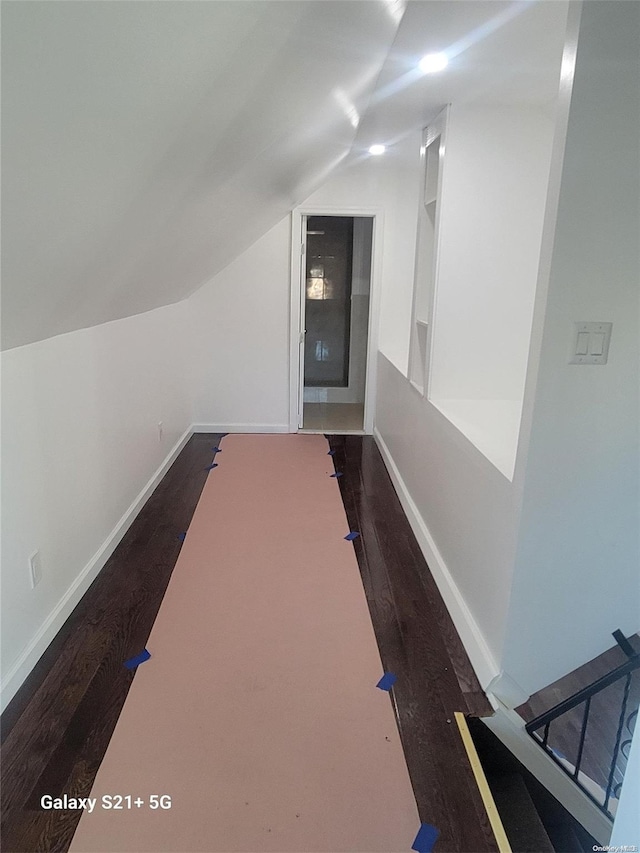 corridor featuring dark hardwood / wood-style flooring and vaulted ceiling