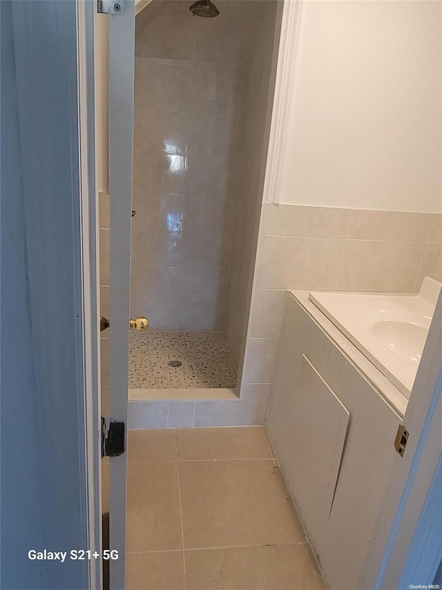 bathroom featuring tiled shower, vanity, tile patterned flooring, and tile walls