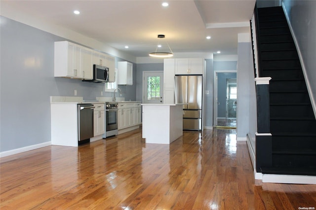 kitchen with white cabinets, stainless steel appliances, and hardwood / wood-style flooring