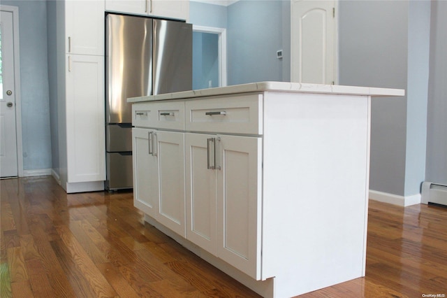 kitchen with baseboard heating, stainless steel refrigerator, white cabinets, and dark wood-type flooring