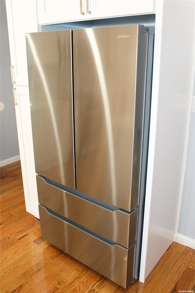 details with white cabinets, light hardwood / wood-style flooring, and stainless steel refrigerator