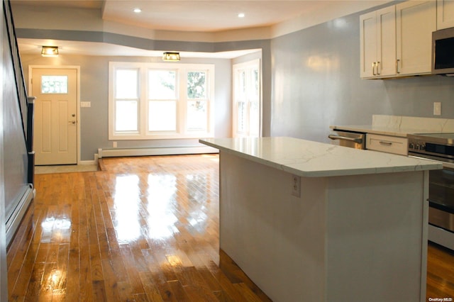 kitchen with a center island, baseboard heating, light hardwood / wood-style floors, white cabinetry, and stainless steel appliances