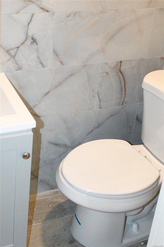 bathroom featuring vanity, toilet, and tile walls