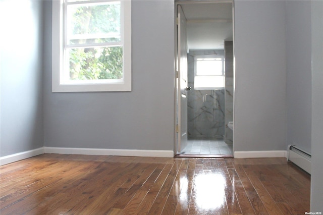 empty room featuring dark wood-type flooring and a baseboard heating unit