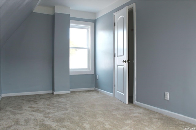 additional living space with light colored carpet and vaulted ceiling