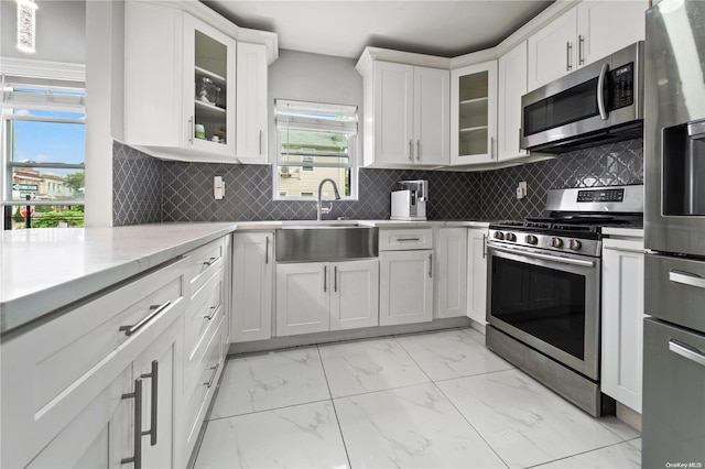 kitchen featuring stainless steel appliances, white cabinetry, sink, and a wealth of natural light