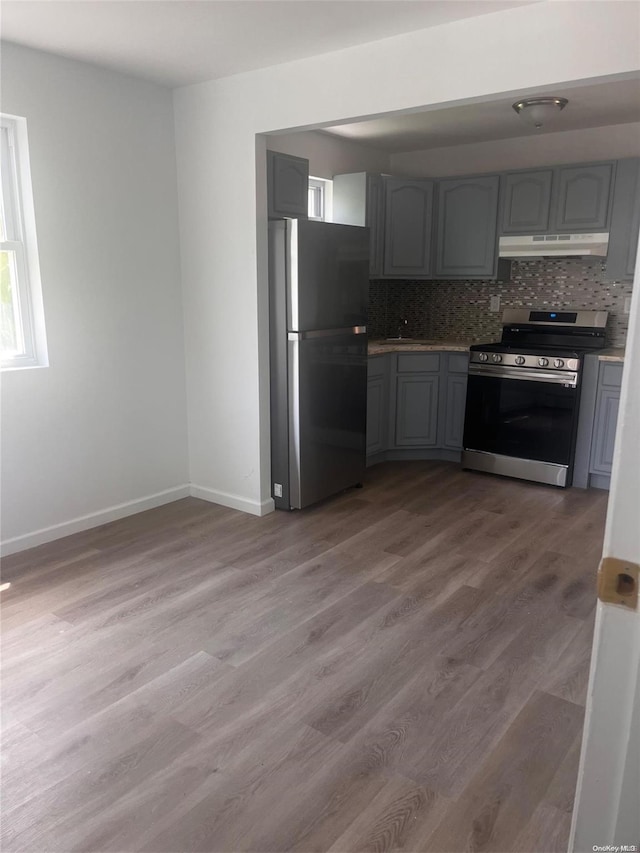 kitchen featuring decorative backsplash, gray cabinets, wood-type flooring, and appliances with stainless steel finishes