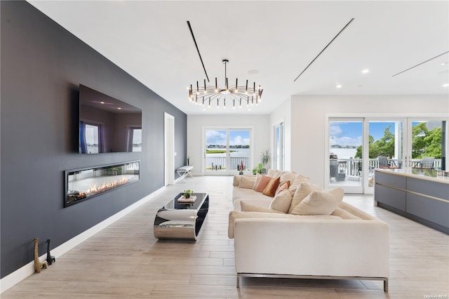 living room with light hardwood / wood-style floors, an inviting chandelier, and a healthy amount of sunlight