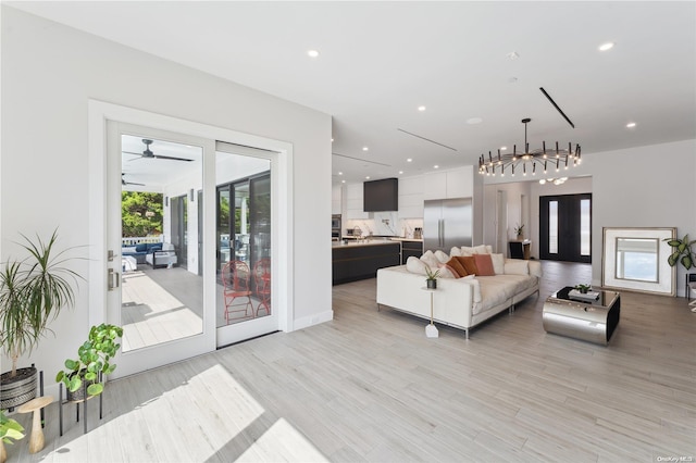 living room featuring french doors, ceiling fan with notable chandelier, and light wood-type flooring