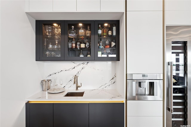 bar featuring backsplash, oven, wine cooler, and sink