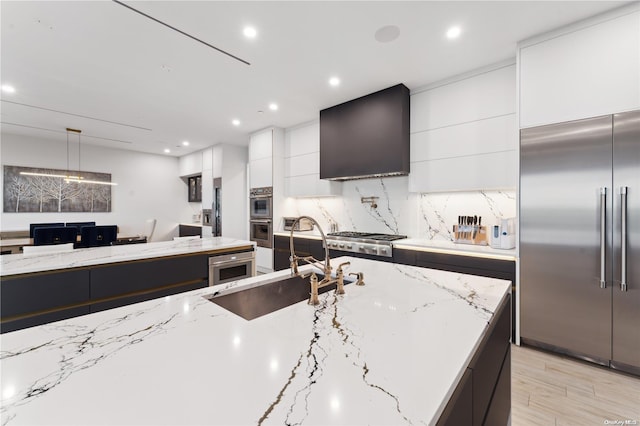 kitchen with sink, light stone countertops, stainless steel appliances, and light wood-type flooring