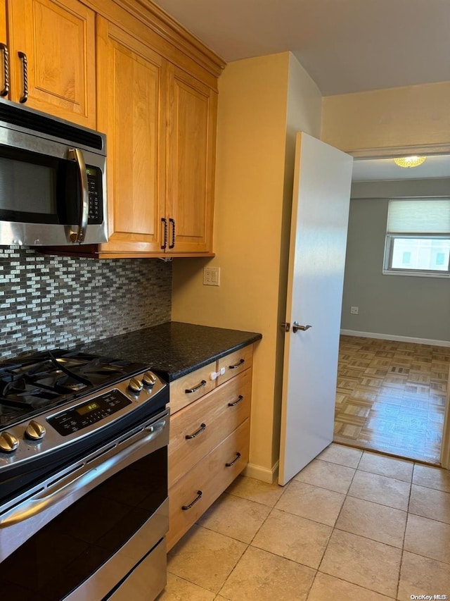 kitchen featuring light tile patterned flooring, dark stone countertops, backsplash, and appliances with stainless steel finishes