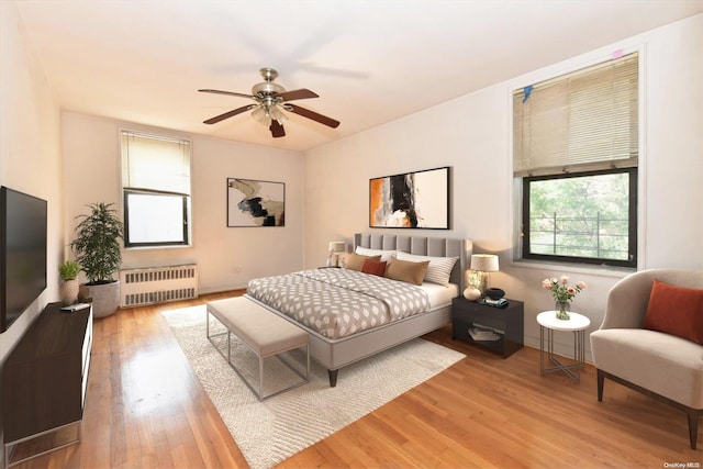 bedroom with hardwood / wood-style flooring, radiator, and ceiling fan