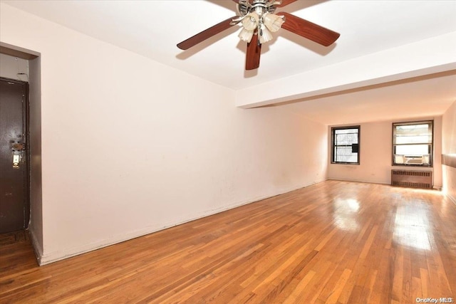 spare room with hardwood / wood-style floors, radiator, cooling unit, and ceiling fan