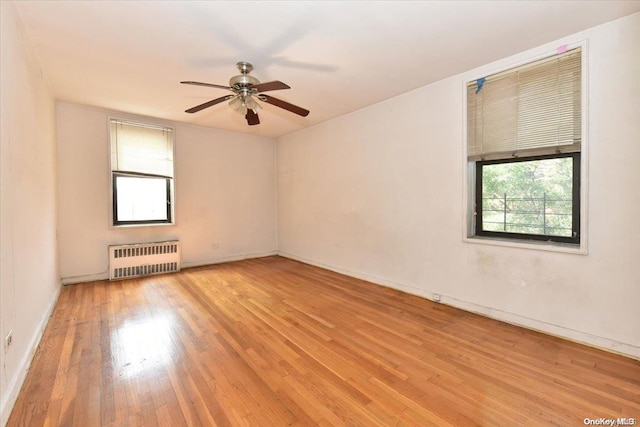 unfurnished room with radiator, a wealth of natural light, ceiling fan, and light hardwood / wood-style floors