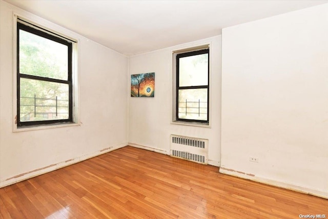 empty room with radiator heating unit and light wood-type flooring