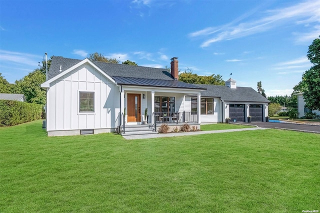 rear view of property with a garage, covered porch, and a yard