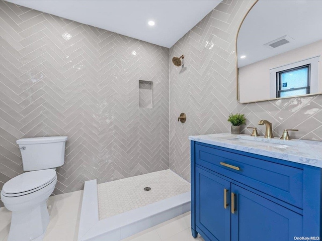 bathroom featuring tile patterned flooring, a tile shower, toilet, and tile walls