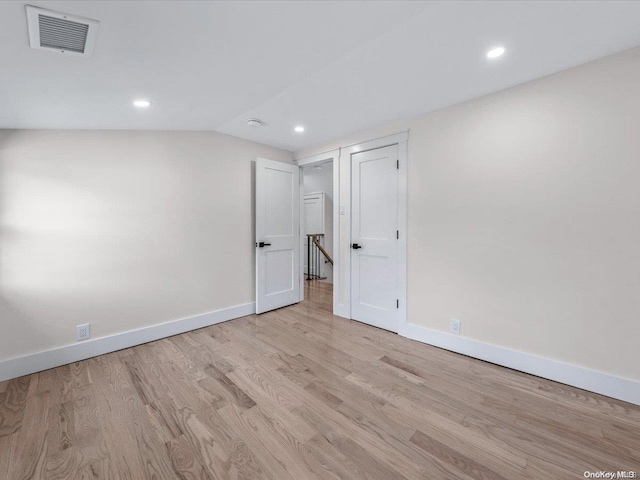 spare room featuring lofted ceiling and light hardwood / wood-style flooring