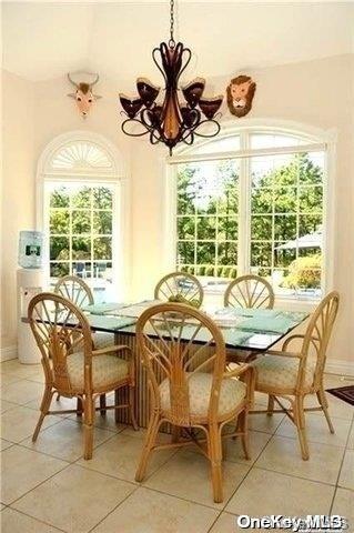 dining room with light tile patterned flooring, a wealth of natural light, and an inviting chandelier