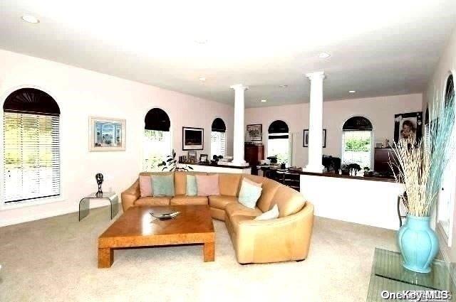 carpeted living room featuring ornate columns