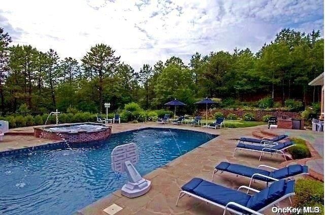 view of swimming pool featuring an in ground hot tub and a patio