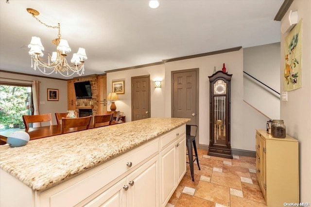 kitchen featuring light stone counters, a breakfast bar, an inviting chandelier, a fireplace, and a center island