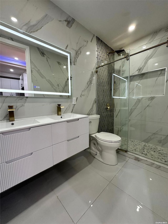 bathroom with tile patterned flooring, toilet, vanity, a shower with shower door, and tile walls