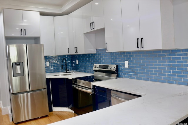 kitchen featuring white cabinets, appliances with stainless steel finishes, light hardwood / wood-style floors, and sink