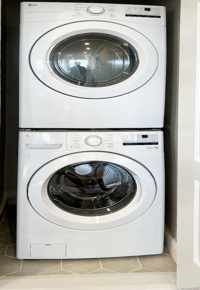 laundry area with light tile patterned floors and stacked washer and clothes dryer