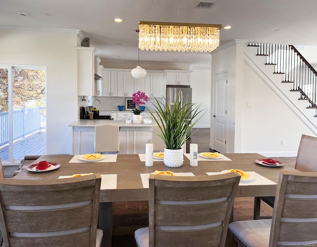 dining area featuring ornamental molding, a notable chandelier, and hardwood / wood-style floors