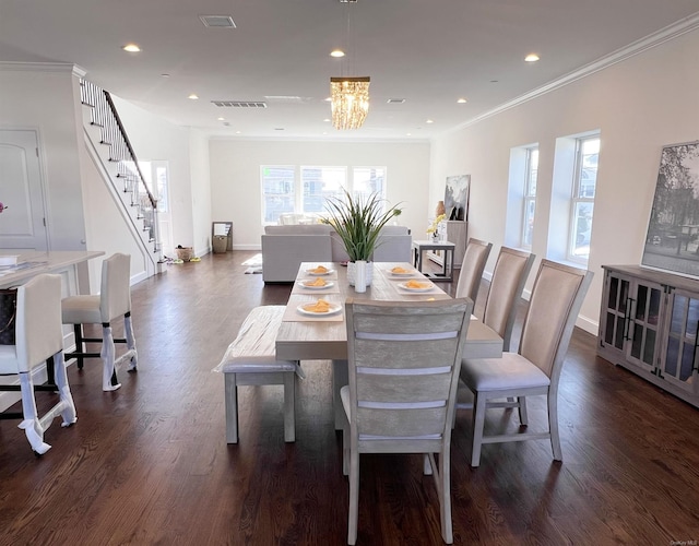 dining area featuring dark hardwood / wood-style floors, a healthy amount of sunlight, crown molding, and an inviting chandelier