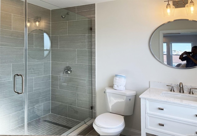 bathroom featuring vanity, toilet, and a shower with door