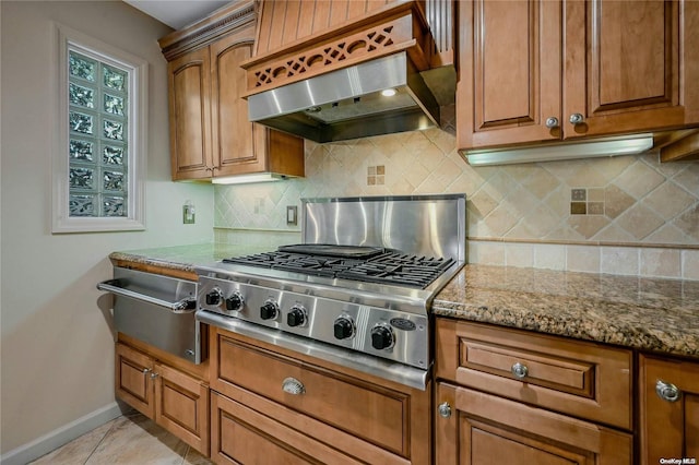 kitchen with backsplash, wall chimney range hood, light tile patterned floors, stone counters, and stainless steel gas stovetop