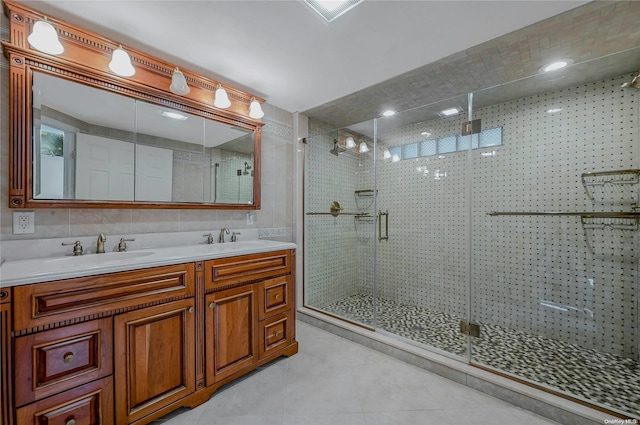 bathroom featuring vanity, a shower with door, tile patterned flooring, decorative backsplash, and tile walls