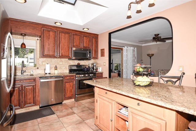 kitchen featuring a skylight, ceiling fan, sink, stainless steel appliances, and backsplash