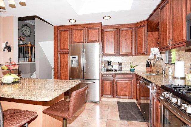 kitchen with sink, decorative backsplash, a breakfast bar, light tile patterned floors, and appliances with stainless steel finishes