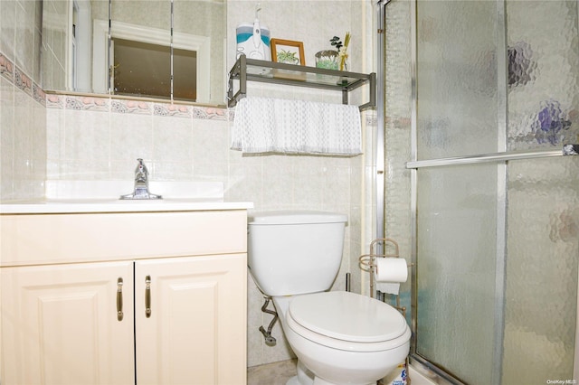 bathroom featuring toilet, decorative backsplash, vanity, a shower with shower door, and tile walls